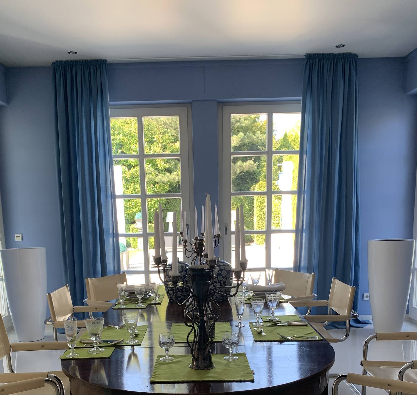 Esszimmer mit blauen Gardinenschals und hellem Store am Fenster