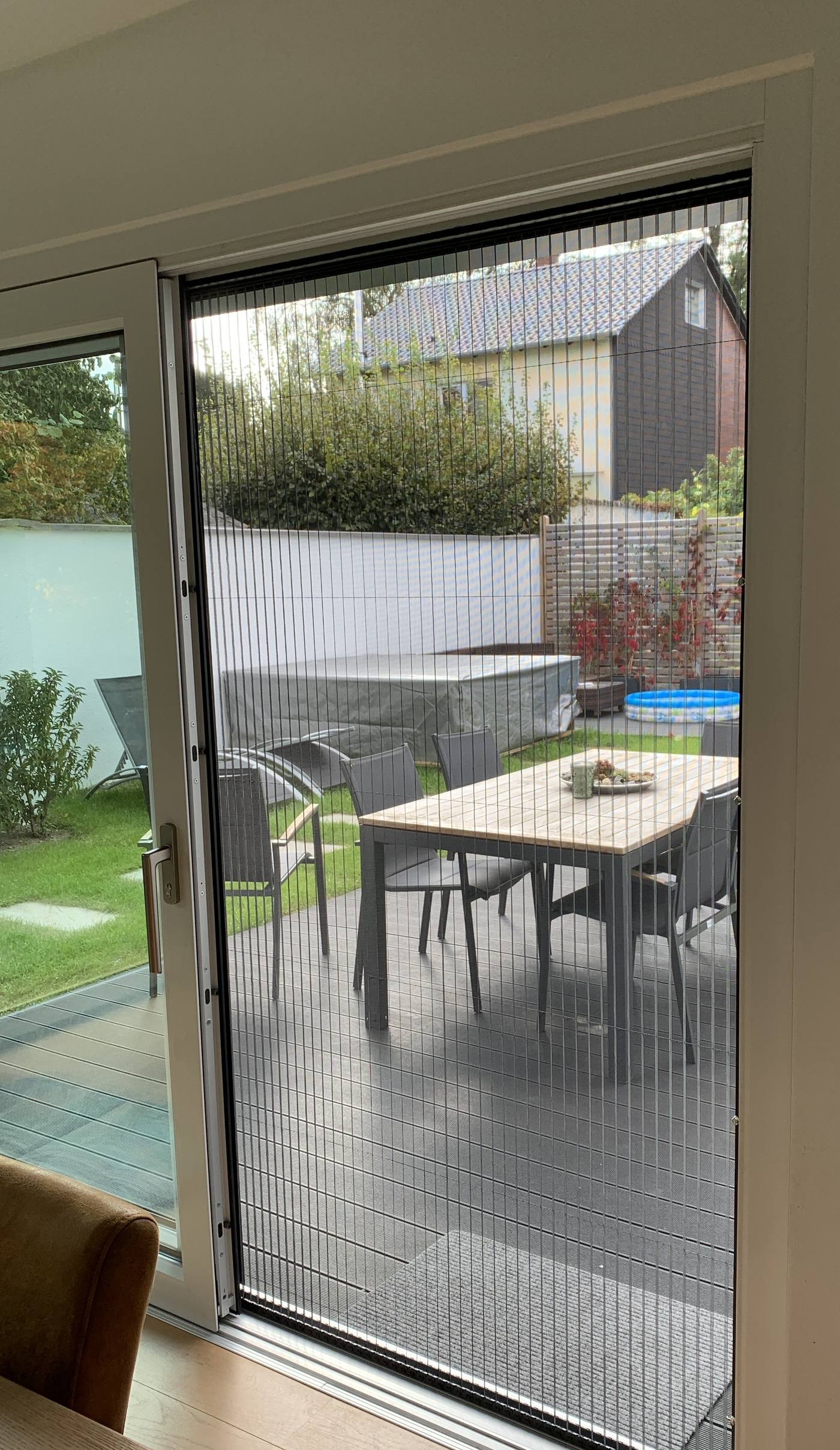 Insektenschutz-Plisseetür an einer Terrassentür mit Blick in den Garten