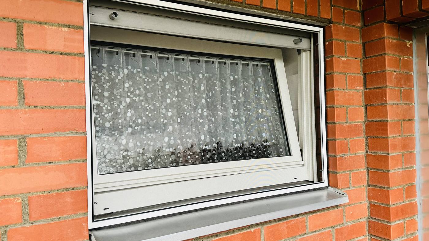 Kellerfenster mit Insektenschutzgitter in einer Klinkerfassade