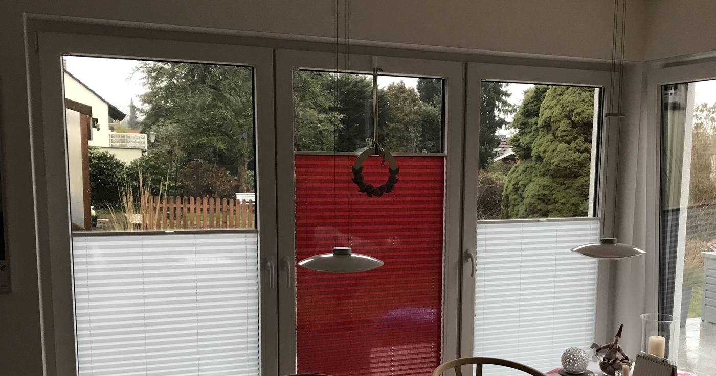 Esszimmer mit Plissees, ein rotes Plissee setzt einen Farbakzent