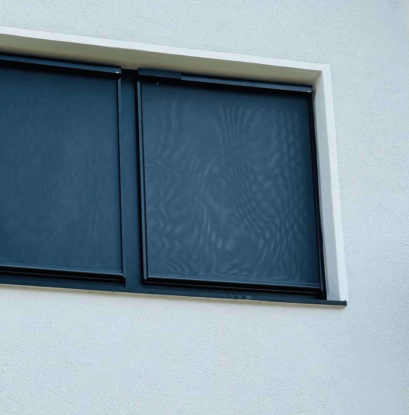 Außenscreen als Sonnenschutz vor einem Fenster an der Fassade