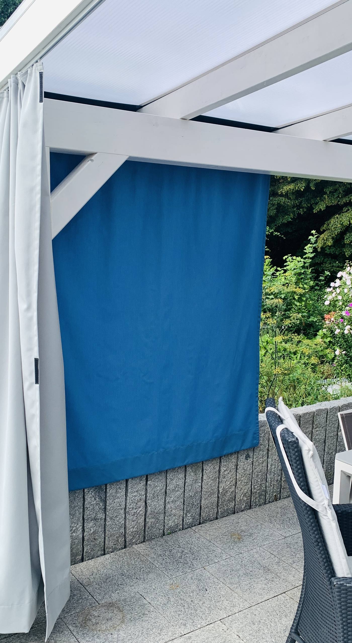 Heller Vorhang in Falten an einer Terrassenüberdachung
